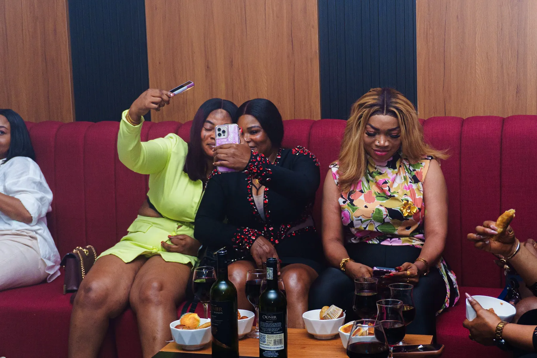 Friends taking a selfie together on a red lounge sofa