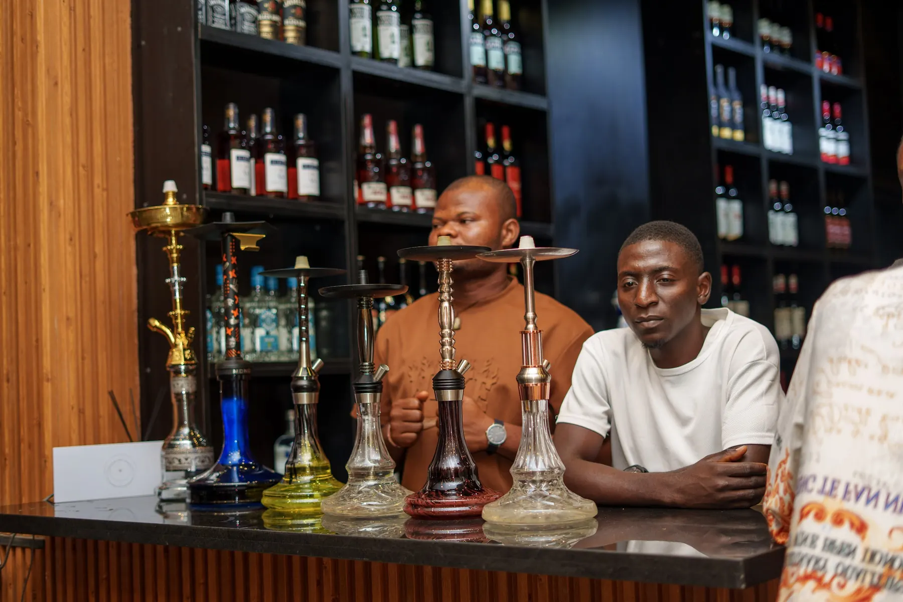 Guests at the bar beside a row of hookah pipes