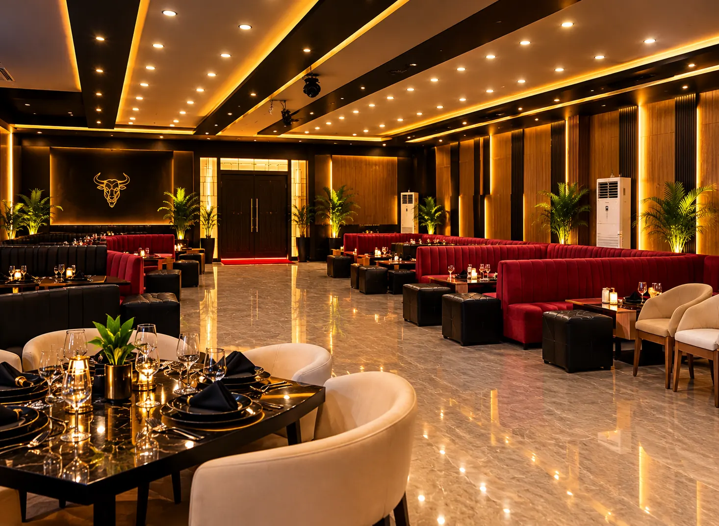 Dining room with set tables, cream armchairs, red booths and warm gold lighting