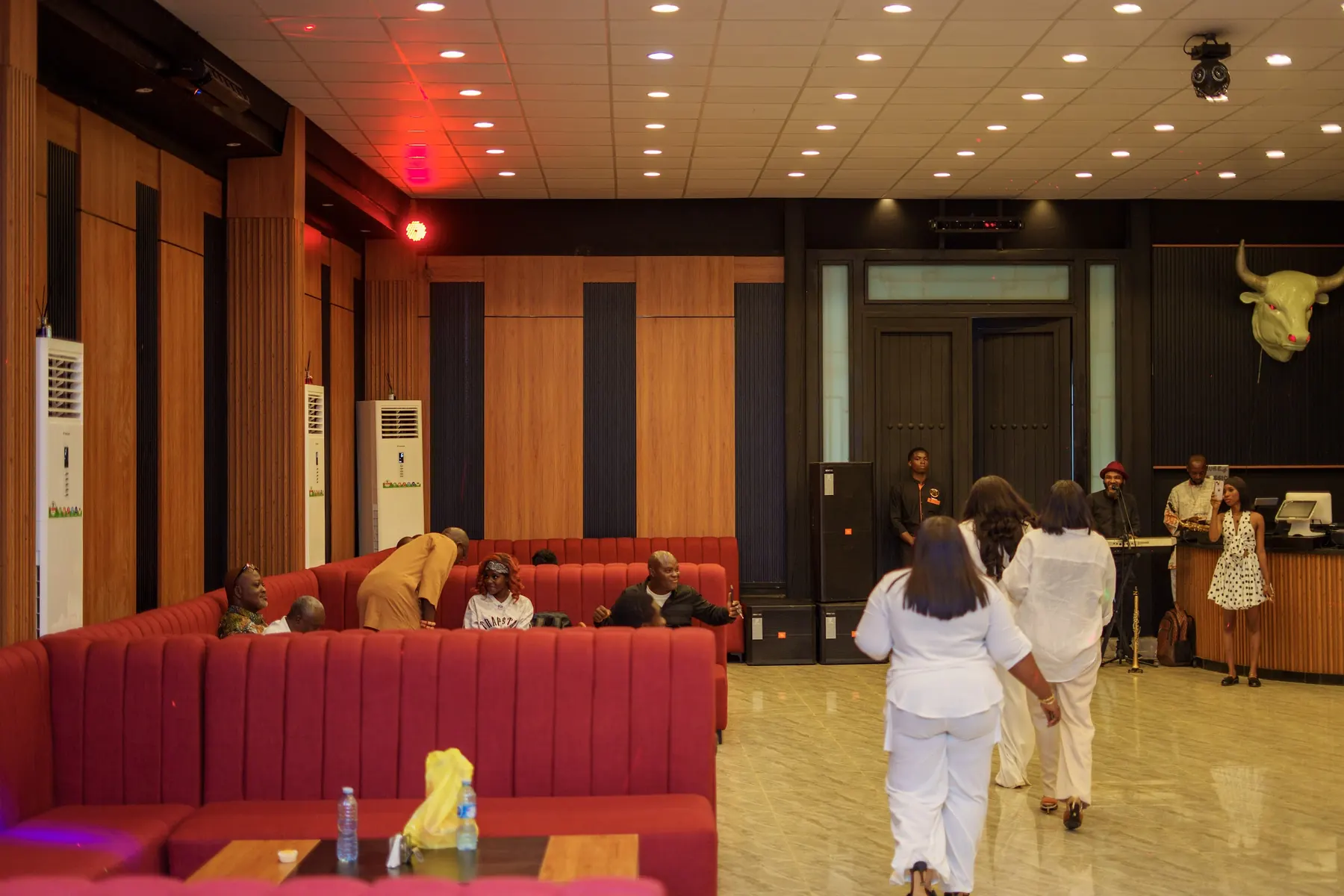 Guests arriving in the lounge with red sofas and wood-panelled walls