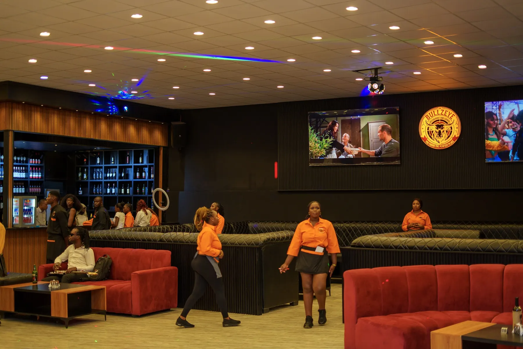 Lounge floor with staff in orange uniforms, red sofas and the bar in the background